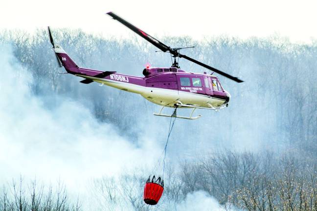 A state forest fire helicopter flies over the fire scene in Vernon at noon on Tuesday.