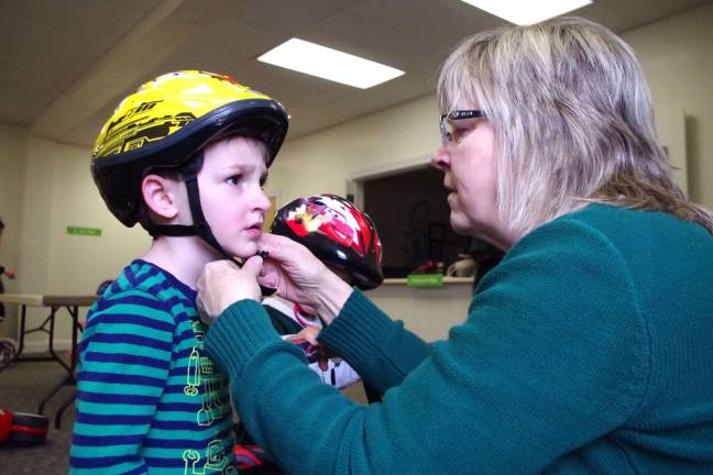 Footprints Montessori School director Mrs. Bjorg Boschen adjusts the helmet of Barry Lakes resident Alex Marsh, 4, during the Trike-A-Thon.