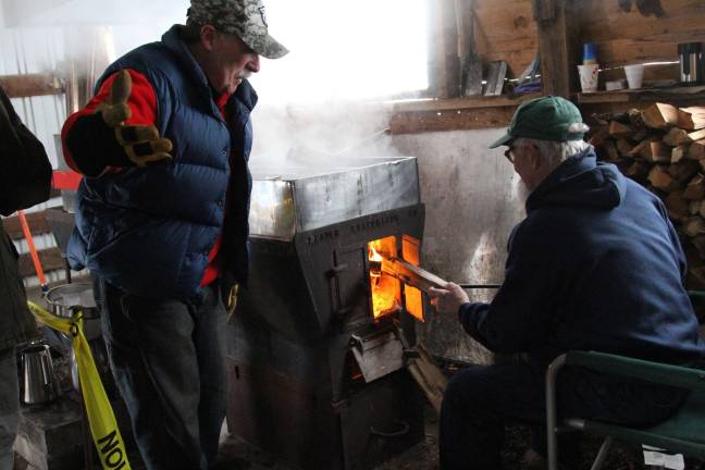 Rick McEnteer and Artie Grimes feeding the fire for the evaporator that reduces the sap into syrup.