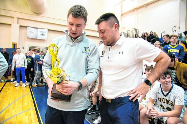 Coach Connor Healy, left, and assistant coach Kodie Hilbert admire the trophy.