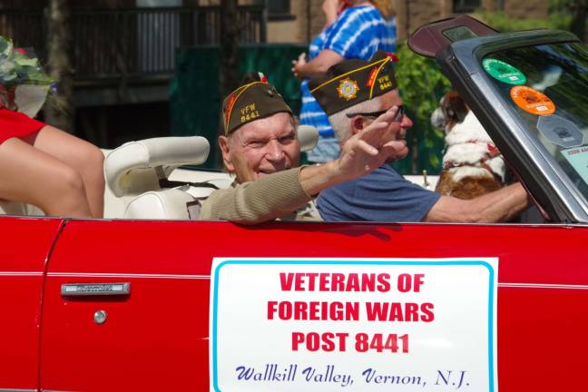 Sitting in the front passenger's seat, Barry Lakes resident Paul Sellentin, 92, is shown riding in a bright red 1974 Chevrolet Caprice convertible near the front of the parade. In the past he was the parade's Grand Marshall. He served in the army in the Pacific Theater during World War II. As a forward observer during the largest bonsai attack of the war, he was recommended to receive the Bronze Star for Meritorious Service. He is the oldest member of the VFW post and one of Vernon's most senior senior citizens.