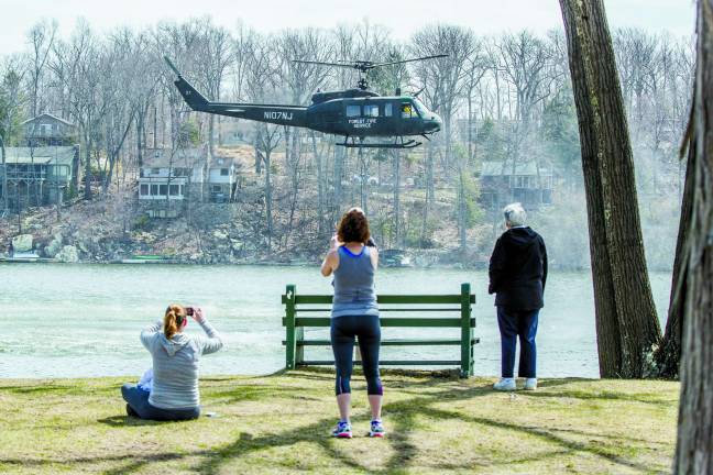 Residents gather at a Highland Lakes Marina to take photos of the state fire service helicopter picking up water to drop on the forest fire in Vernon on Tuesday afternoon.