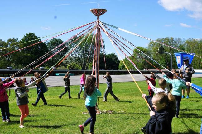 First-graders weave a pattern with 24 ribbons on the May Pole.