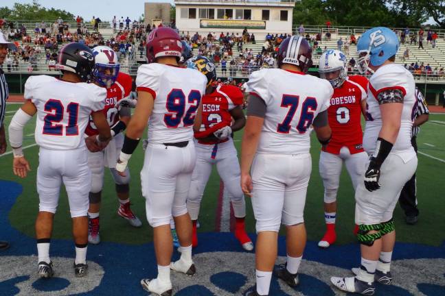 East and West players shake hands before coin toss at midfield.