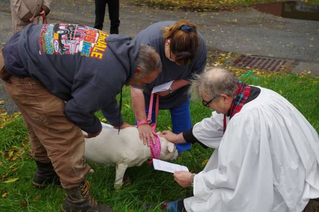 Princess receives her blessing and a treat from the Rev. Dr. Howard W. Whitaker as her humans, Bob and Kathy Winter, of the Vernon Valley Lakes section of Vernon comfort her.