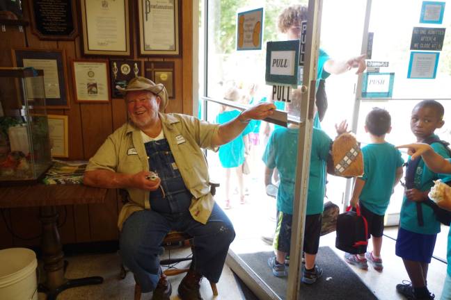 With a baby opossum in hand, Space Farms Senior Zookeeper Fred Space holds the door for campers arriving from the Town of Wallkill Summer Camp.