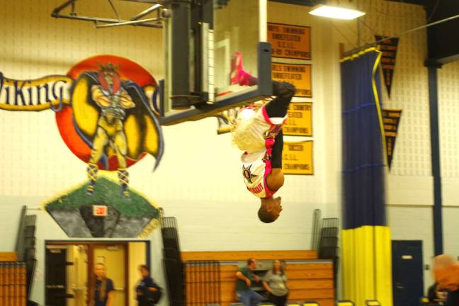 Vernon firefighters take on the Harlem Wizards Devon "Livewire" Curry is shown hanging upside down from the hoop.