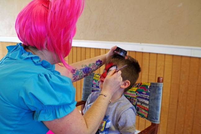 Bryan Miller, 7, of Barry Lakes is shown having his face decorated by &#xec;Pixie Pop&#xee; portrayed by artist Terry Tobin of Highland Lakes.