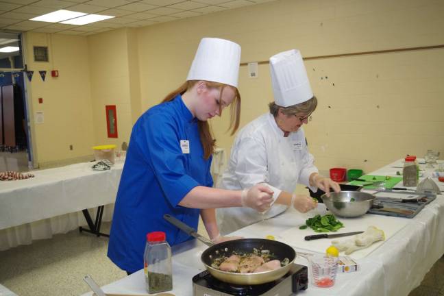Lead student chef Ashley Weigel and Teacher Chef Kathy Weyant of The Inforno team are shown preparing what would end up being the winner dish for the evening, lemon pepper chicken served over garlic couscous. Additional team members were Cassidy Braico, Steve Owens, and Taryn Stolzenberg.
