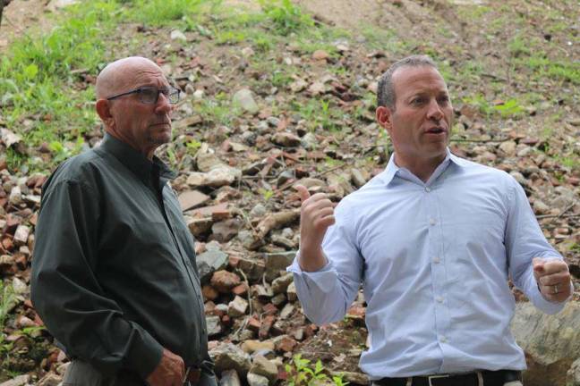 U.S. Rep. Josh Gottheimer, right, assesses the waste pile alongside Vernon Mayor Harry Shortway, Jr. left. In the background, rebar, cement, asphalt, and rusted piping can be seen mixed in among the waste.
