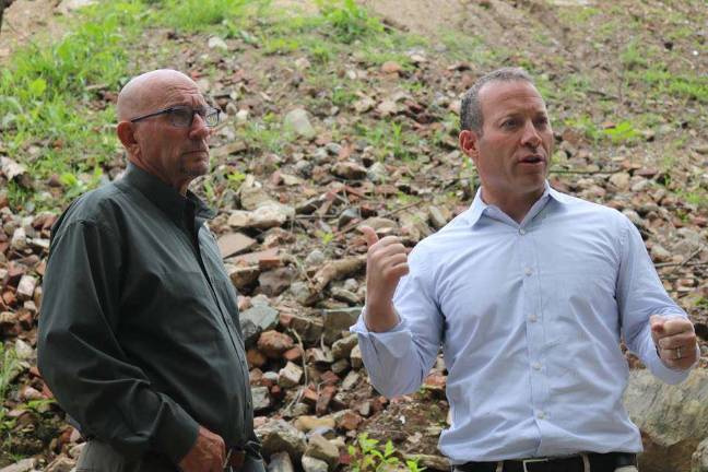 U.S. Rep. Josh Gottheimer, right, assesses the waste pile alongside Vernon Mayor Harry Shortway, Jr. left. In the background, rebar, cement, asphalt, and rusted piping can be seen mixed in among the waste.