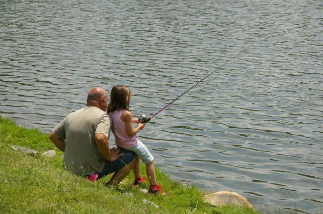 Gabriella Cefaloni, 6, sits on her father Joe's knee while she fishes.