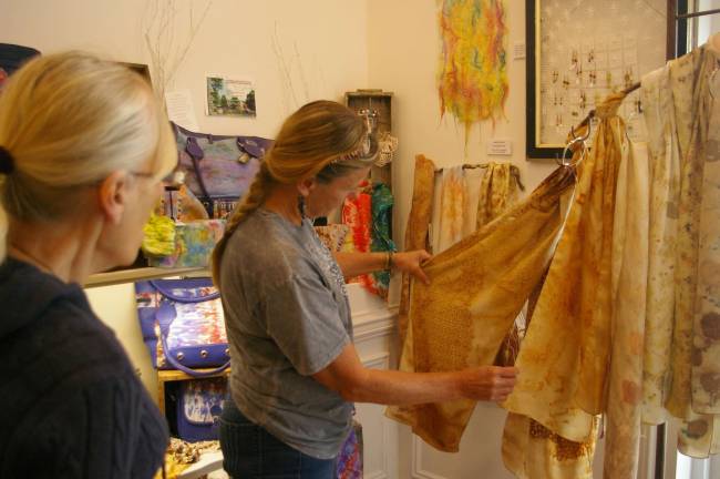 Phylis Barfoot shows a visitor one of her eco printed scarves. The beautiful designs are created by using plants and rusted iron to stain the silk.