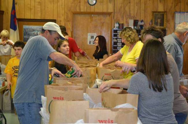 Labor Commissioner Harold J. Wirths helps volunteers at the Sussex United Methodist Church bag complete Thanksgiving dinners that were distributed to families in need through the Sussex Help Center.