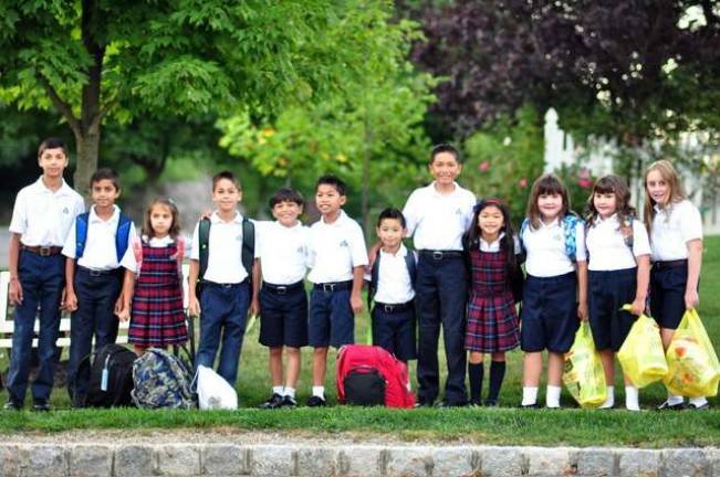 A group of Reverend Brown students wait for the bus on their first day of school. They arrived to find a new fab lab, a one-to-one iPad computing initiative and an upgraded lunch program.
