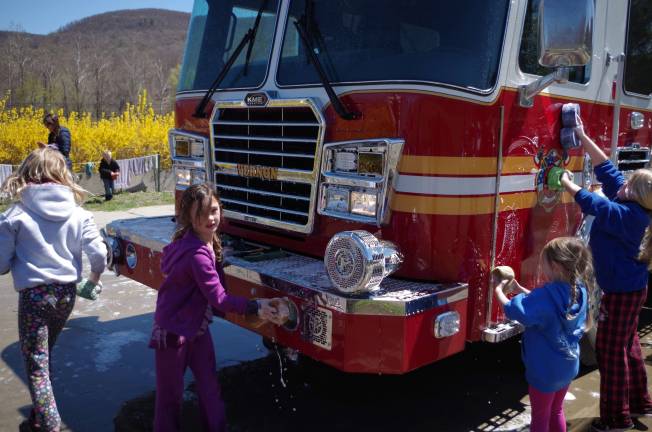 Vernon Girls Softball League player Monica Curry (7) helps her fellow players wash a Vernon Township Fire Department truck. Curry plays for the Dairy Queen Rookies.