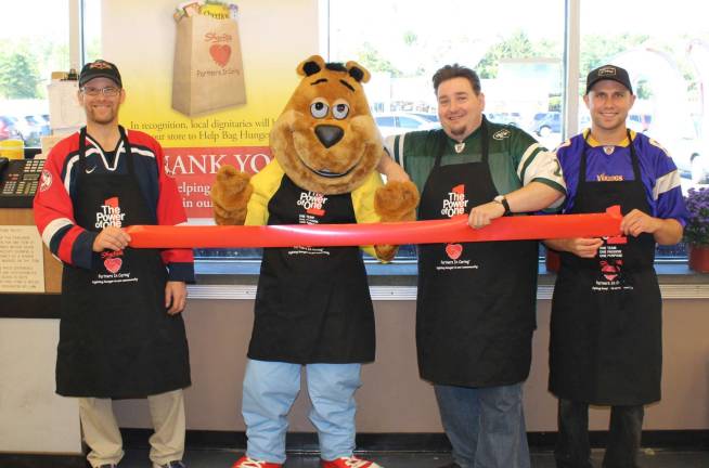 From left, sports fans Ted Kwasnik, Scrunchy the Bear, Ed Massey and Dan Halbach bagged groceries in Byram.