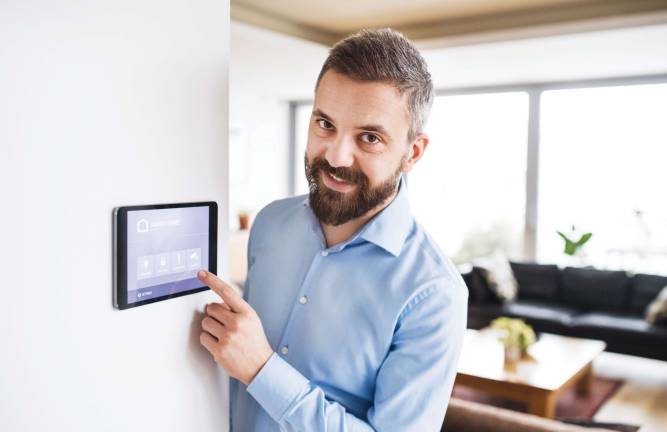 An handsome man pointing to a tablet with smart home control system.