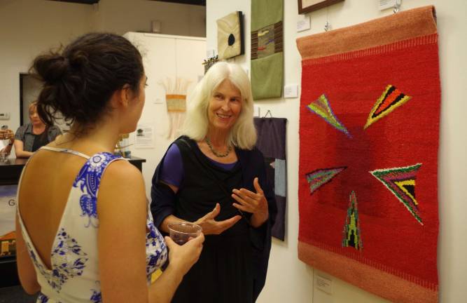 Artist Carol Chave, of Highland Lakes and New York City, speaks with one of attendees of the Skylands Gallery art opening about her handwoven tapestry wall hangings.