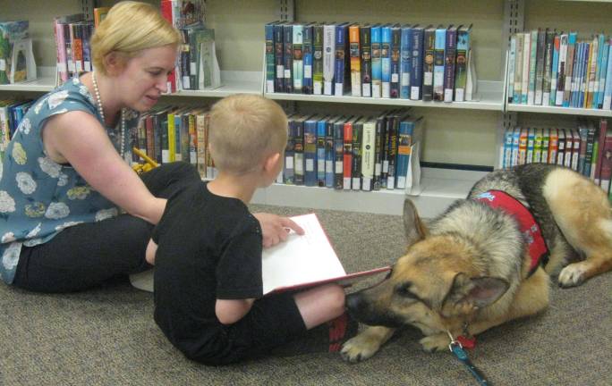 Therapy dog visits library Mom Brooke and Brandon Babcock collectively read to Wren.