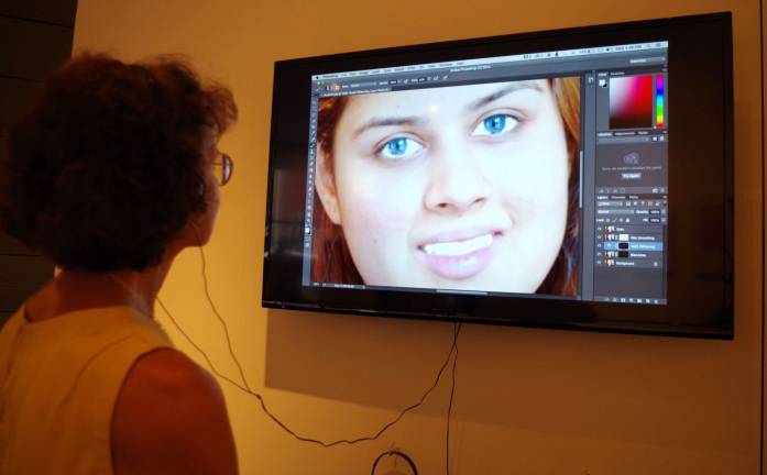A gallery visitor watches a video about the pitfalls of overusing and abusing the popular Photoshop software.