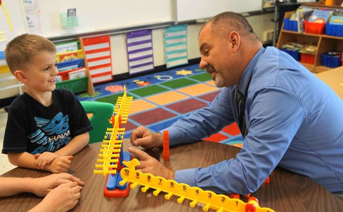 From right, Math Supervisor Russell Rogers works with Christopher on the number line balance beam.