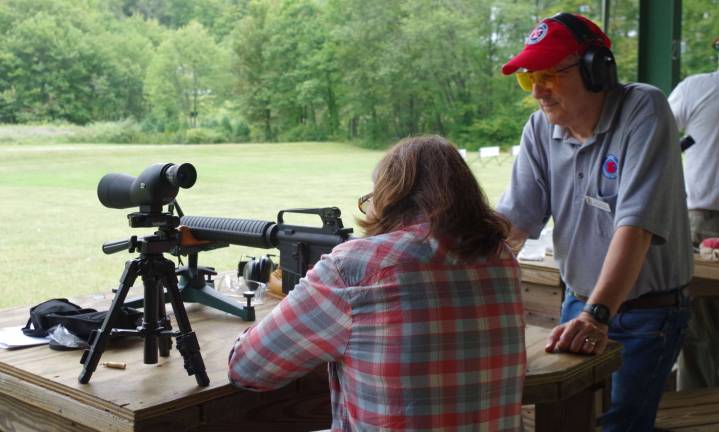 At right, nationally certified firearms instructor Paul Dunberg works with a female visitor at the high power range.