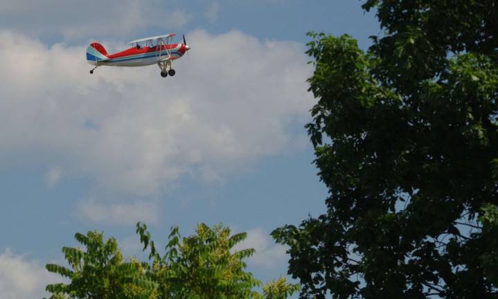 A vintage biplane is shown taking off from Sussex Airport.