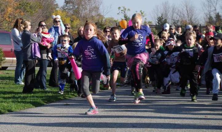 With their feet barely touching the ground, two members of Girls on the Run organization lead the costumed runners during last Saturday's Monster Mile Race at Maple Grange Park.