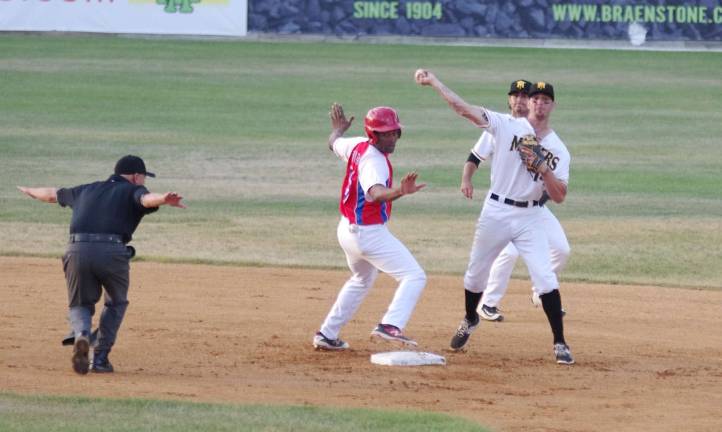 An official and Cuban runner Yoelvis Fiss give the safe signal during a double play attempt by the Sussex Miners.