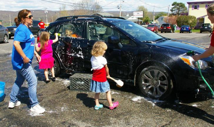 At left, volunteer car washer Laura Constantine supervises her young helpers as another child in the backseat of the car teases one of them.