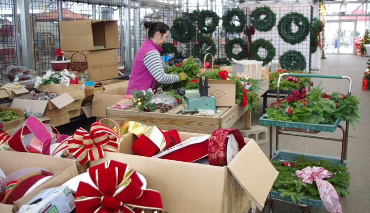 With dozens of boxes of bows and ribbon and much more, Maria Gutirrez is shown creating Christmas wreaths at Heaven Hill Farm.