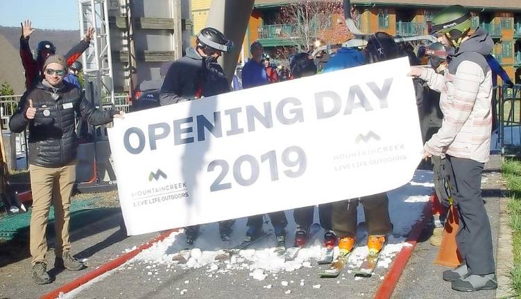 Evan Kovach, left gives a thumbs up as the Majka’s and Klein”s break through the Opening Day Banner.