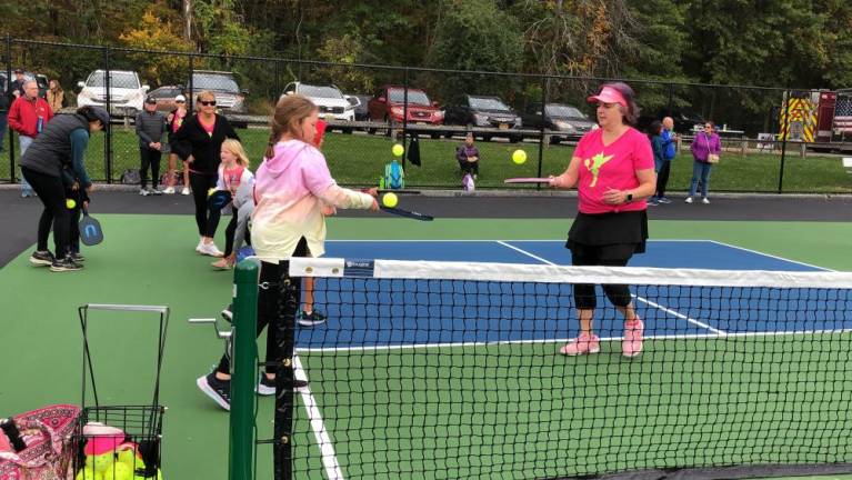 Nina Sutera, right, of Ogdensburg shows children how to bounce the ball on their paddles.