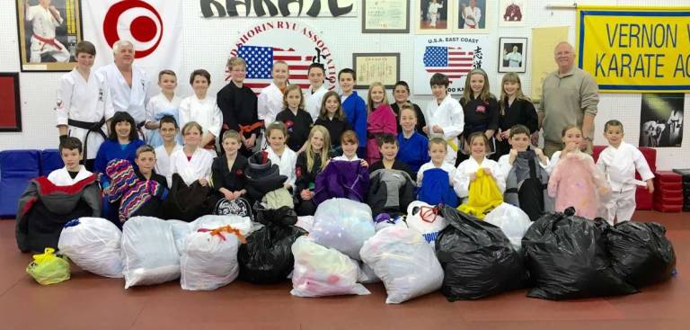 Students at the Vernon Valley Karate Academy donate clothes they collected to benefit families in need during these cold winter months to Retired Lieutenant Gary Gardner of the Vernon Police Department.