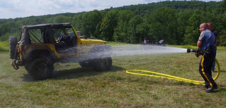 The Hardyston Volunteer Fire Department sent a tanker truck to the scene for a $5 per Jeep mud removal spray. Taking his turn at the spray nozzle is Hardyston Township Police Department Sergeant Ed O'Rourke.