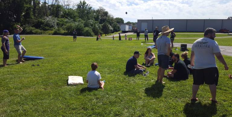 Miller Bros. hosts seminar, BBQ Tom Kelly (left, blue) throws a beanbag during a game of cornhole at the BBQ portion of the event.