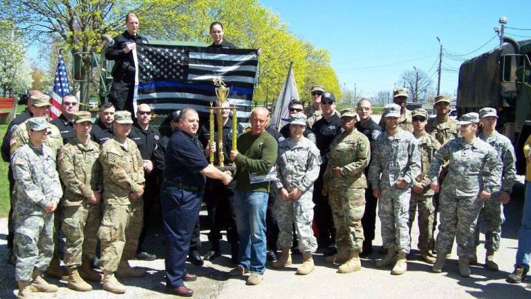 Warden Mark Farsi holds up the trophy surrounds by members of the SOG Team and members of the military.