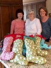 Club President Lois Marples (center) sewed the stockings using colorful holiday fabric. She is flanked by Public Issues Committee Chair Debra Piccirillo (right) and Committee member Judy Phillips (left) who helped stuff and ship the stockings.