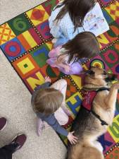 <b>Children read to a therapy dog at the library’s Dennis branch. Photo provided.</b>