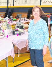 <b>Joann Lisa of Vernon stands in front of a table.</b>