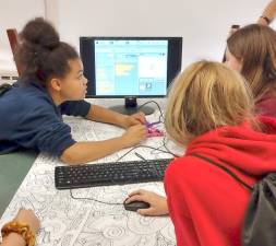 Girls work together to code a robotic hand.