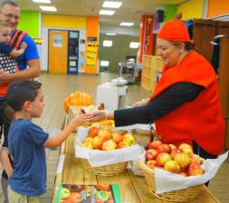 PHOTOS BY VERA OLINSKI On right, Cindy O'Donnell offers an apple to a little boy.