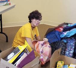 Aileen Itter sorts new backpacks donated to Project Self-Sufficiency for distribution to needy children.
