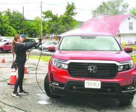 <b>Taylor Tittle of Vernon sprays down a car.</b>