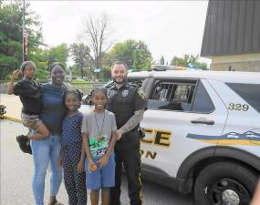 A family stands with School Resource Officer Sean Perry in front of a “Touch-a-Truck” vehicle.