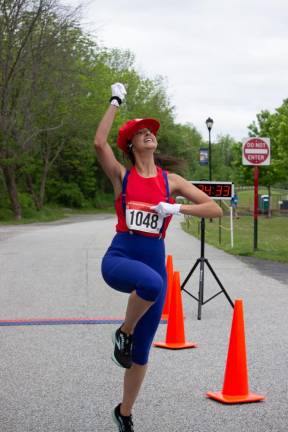 Amy Hackett, 36, of Glenwood, dressed as Super Mario, imitates his notorious hop after crossing the finish line. She was the fastest woman and placed fifth overall with a time of 24 minutes 30.9 seconds.