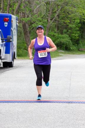 Ewa Bressler of Sussex smiles as she crosses the finish line in Maple Grove Park.