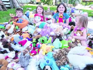 <b>Children sit among stuffed animals.</b>