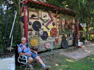 Beemerville artist Wayne Card sits by his ‘Potsdamn Wall.’ (Photo provided)